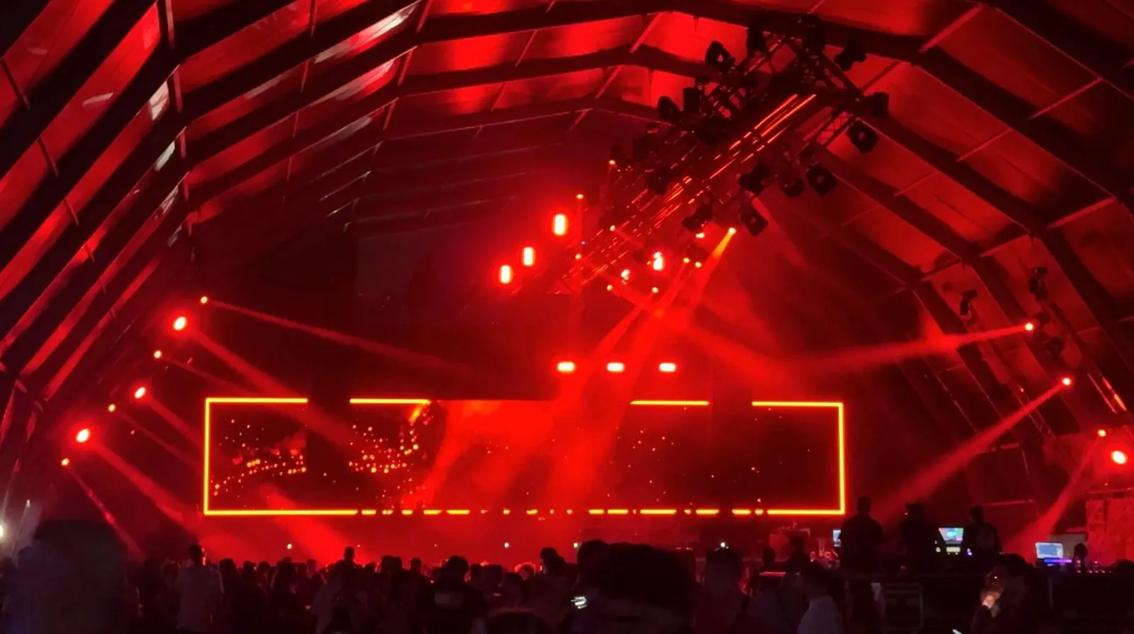 Escenario de festival con iluminación roja y marco dorado
